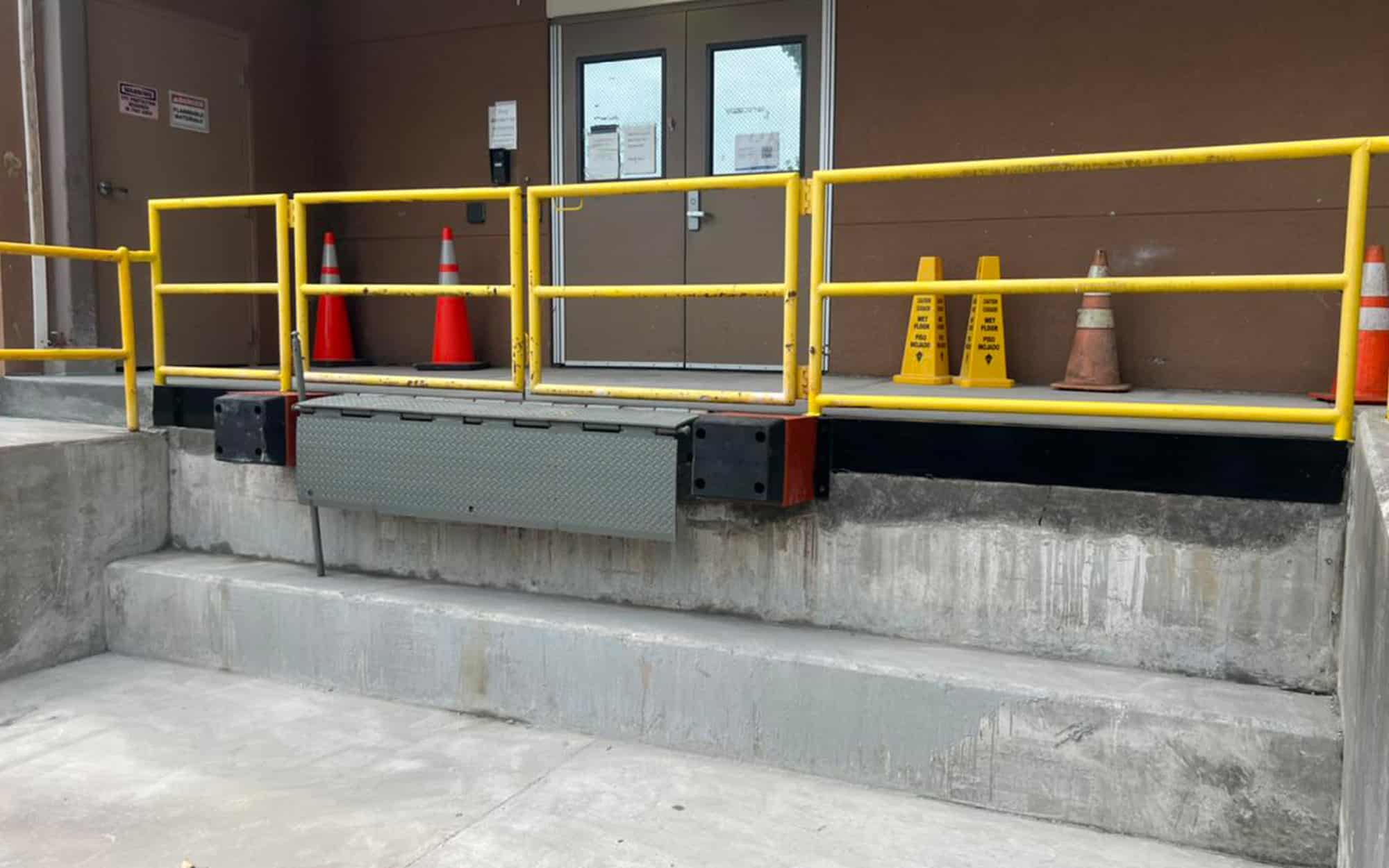 Safety ramp with yellow handrails and traffic cones at Kodiak Equipment Services facility.