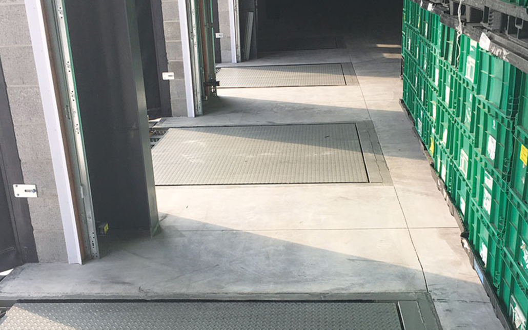 Warehouse entrance with safety mats and green storage bins.