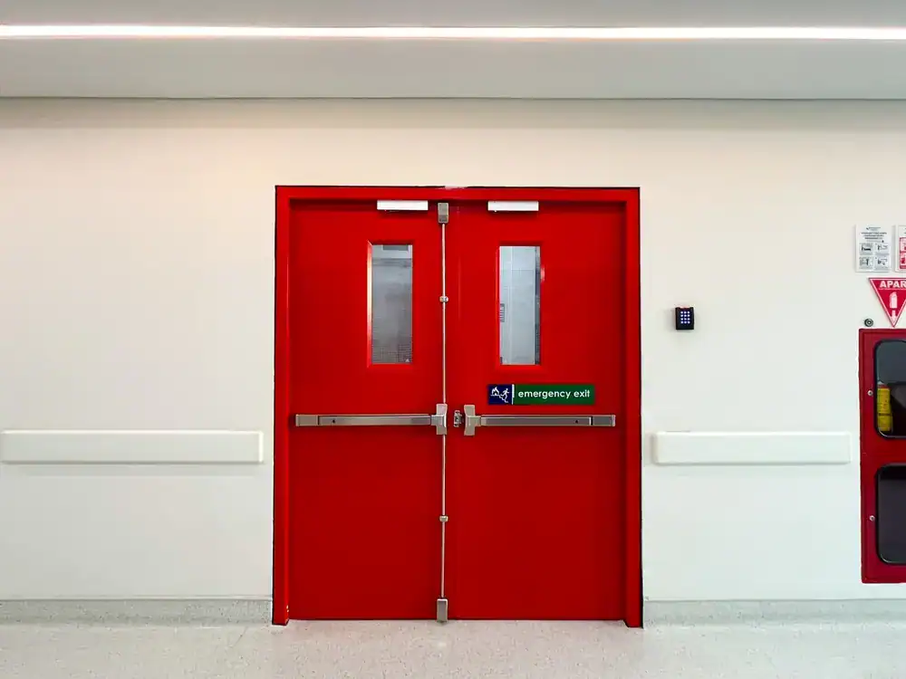 Red emergency exit doors in a commercial building hallway.